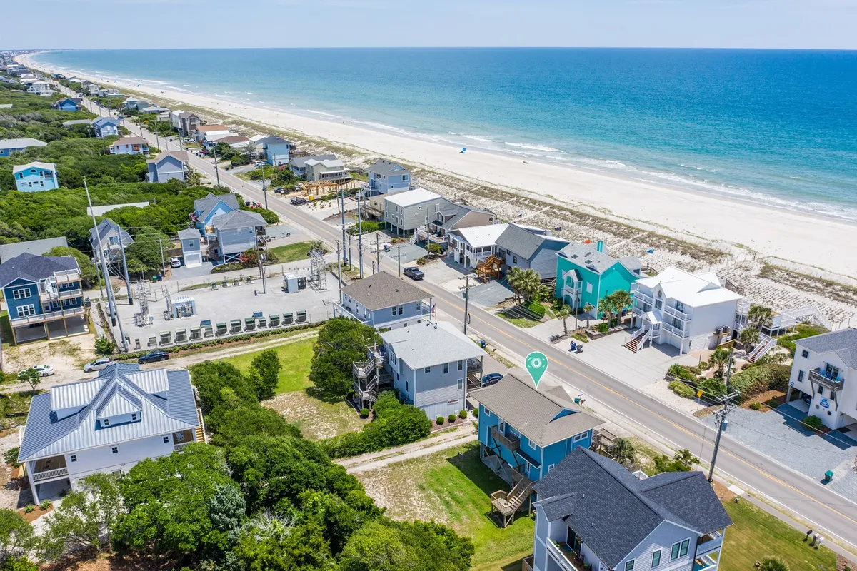 A scenic view of colorful beachfront houses with the ocean and a wide sandy beach in full view. Children and families can be imagined playing or building sandcastles, and the bright, airy mood captures the joyful spirit of a beach vacation.