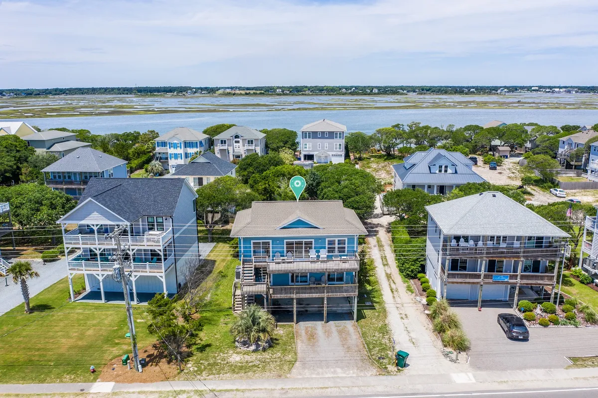 A welcoming, wide exterior shot of several houses with driveways and green surroundings. The image showcases ample parking areas in front of the homes, with easy, open access for unloading and coming inside after travel or beach excursions.